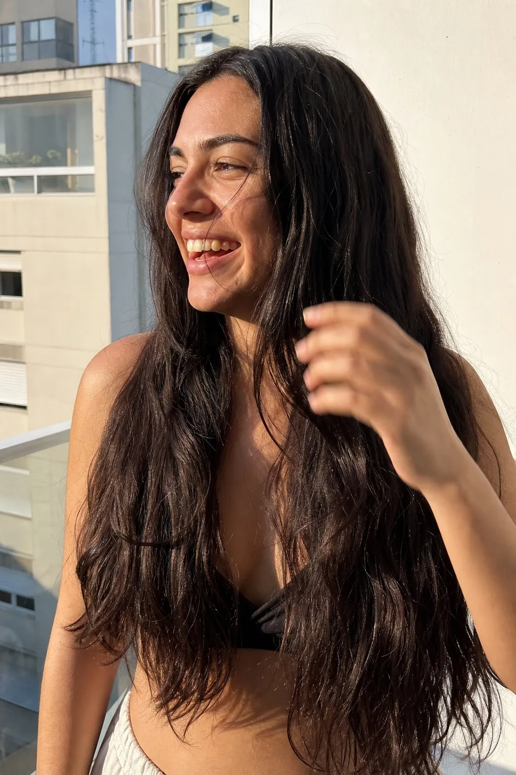 A woman on a sunny balcony before and after face-framing layers - before