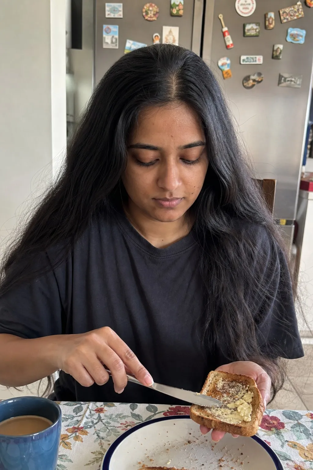 A woman buttering toast at a kitchen table before and after a wolf cut - before